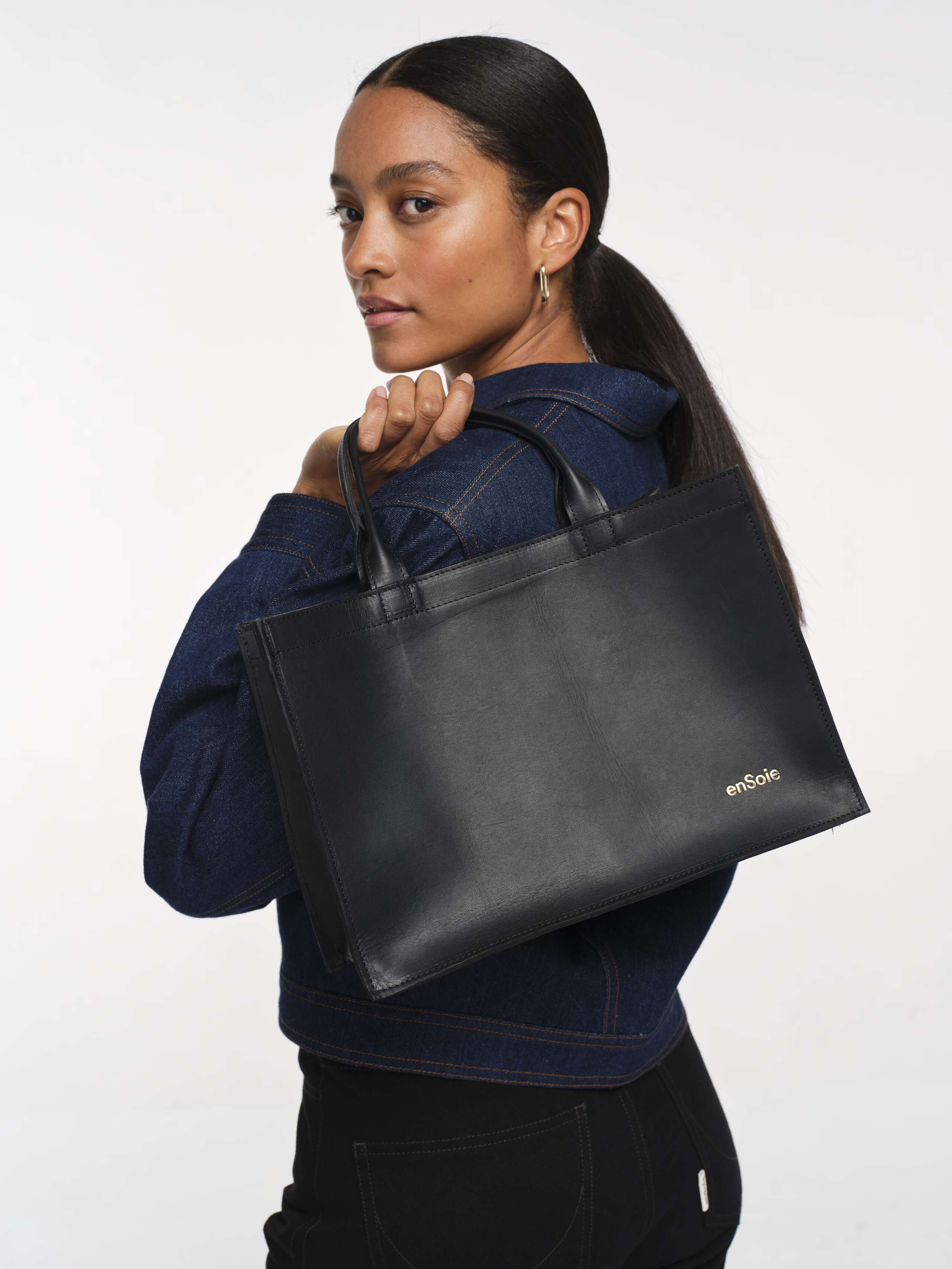 back detail shot of model holding big black leather library bag over her shoulder