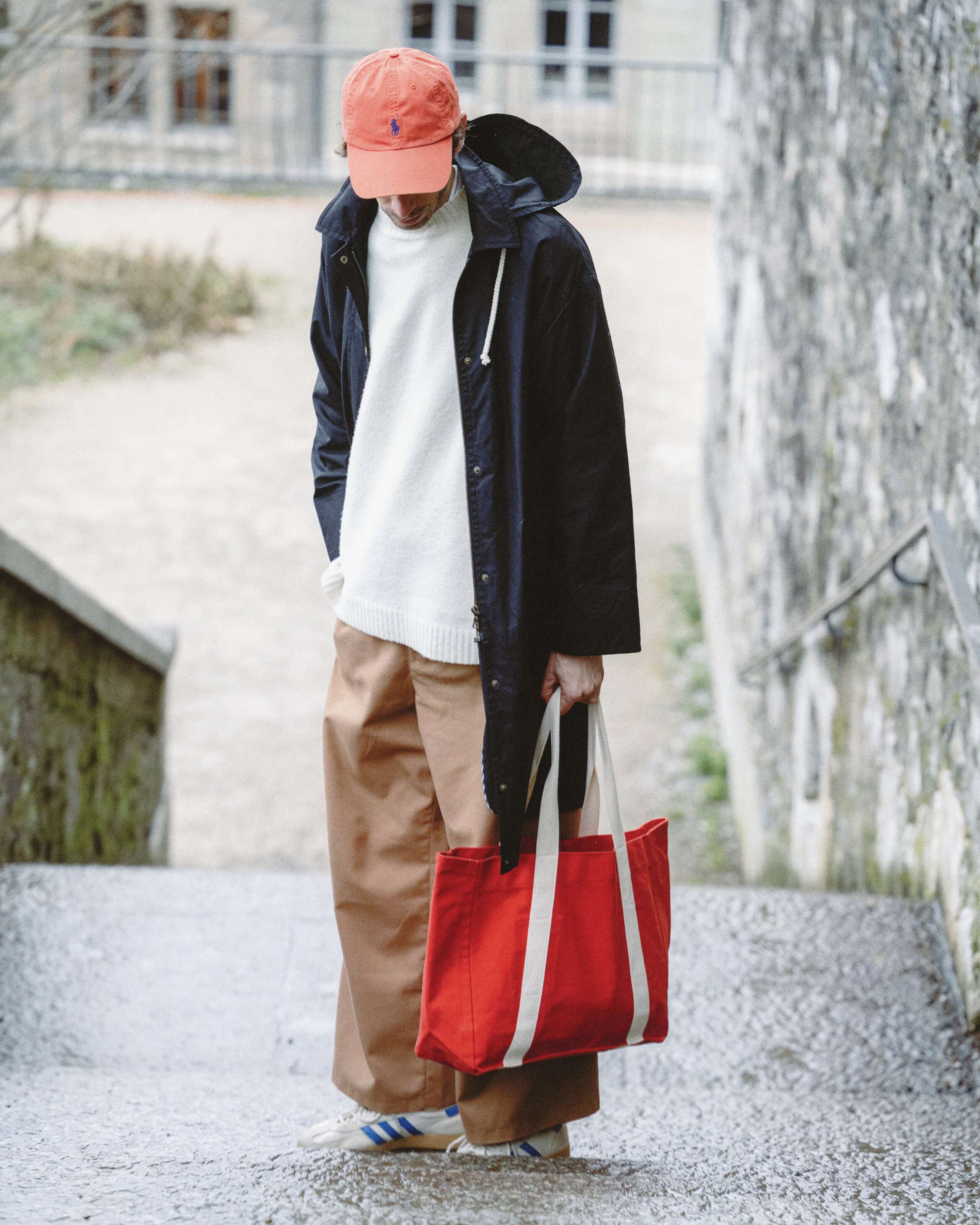 Picture of a man in Geneva, wearing a black enSoie raincoat and carrying a red bag
