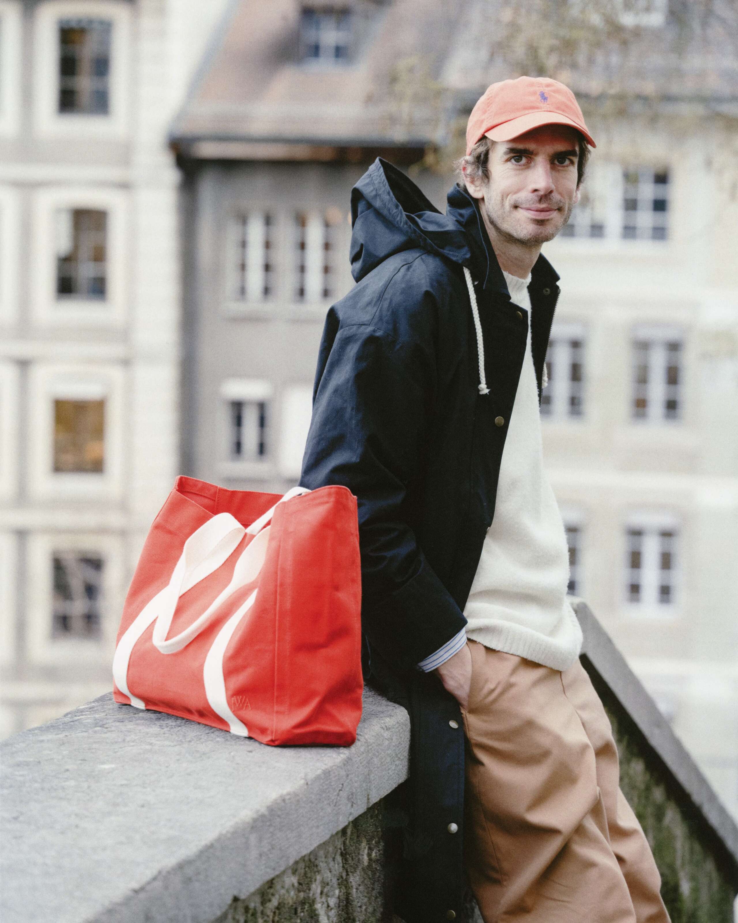 Picture of a man in Geneva, wearing a black enSoie raincoat and carrying a red bag