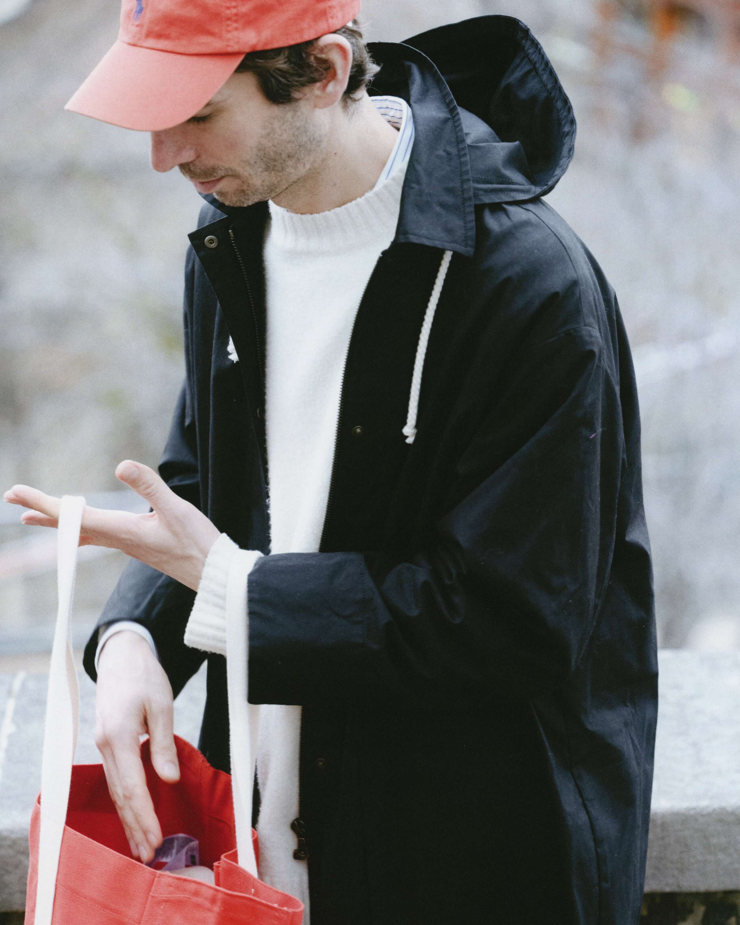 Picture of a man in Geneva, wearing a black enSoie raincoat and carrying a red bag