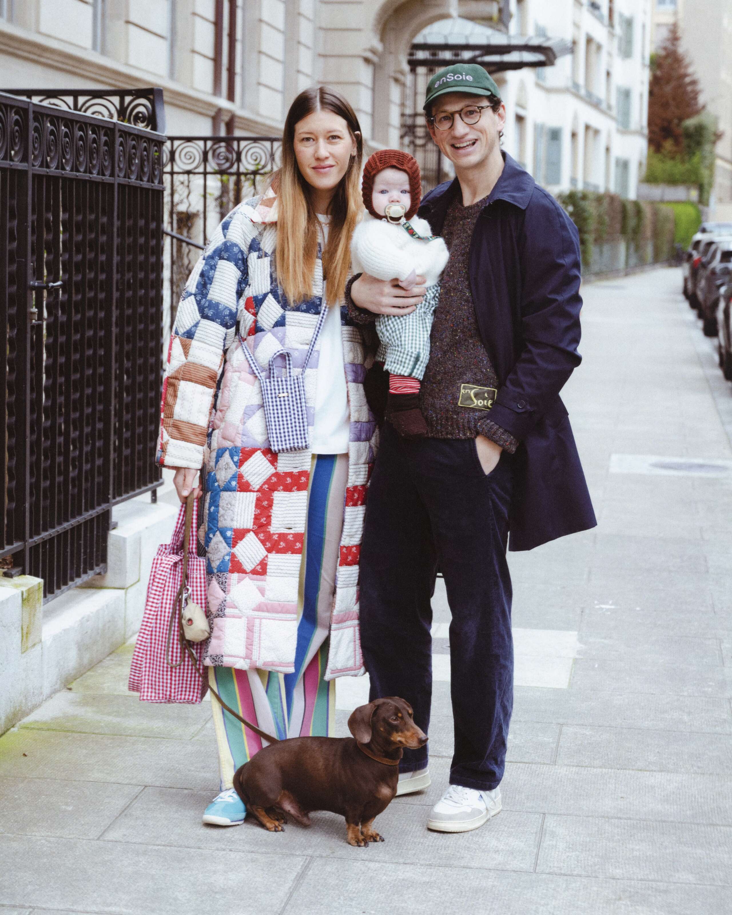 Picture of a couple with baby. They are colourfully dressed. He is wearing an enSoie cap. She carries a classic Cabas bag featuring a red vichy check pattern.