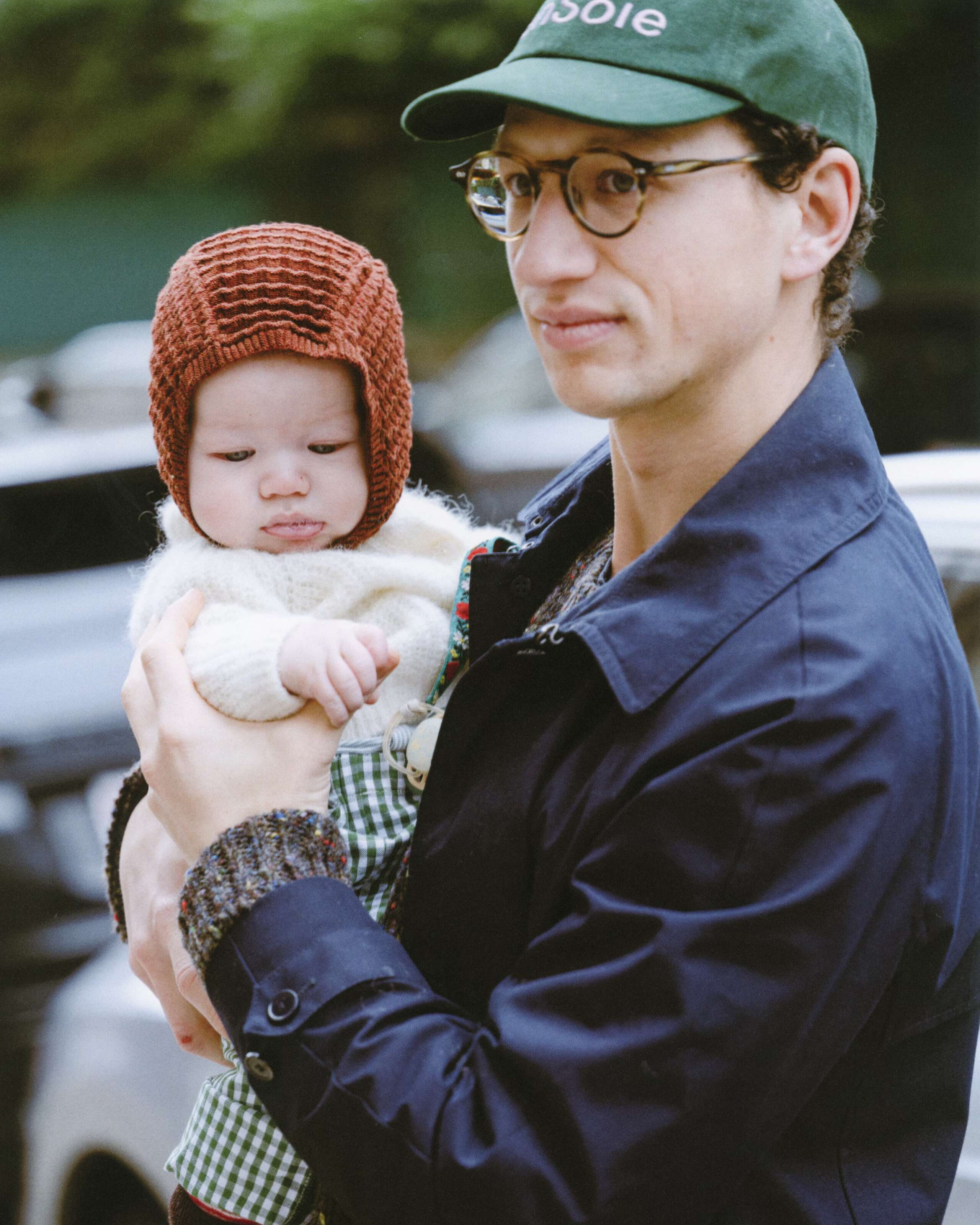 Picture of a couple with baby. They are colourfully dressed. He is wearing an enSoie cap. She carries a classic Cabas bag featuring a red vichy check pattern.