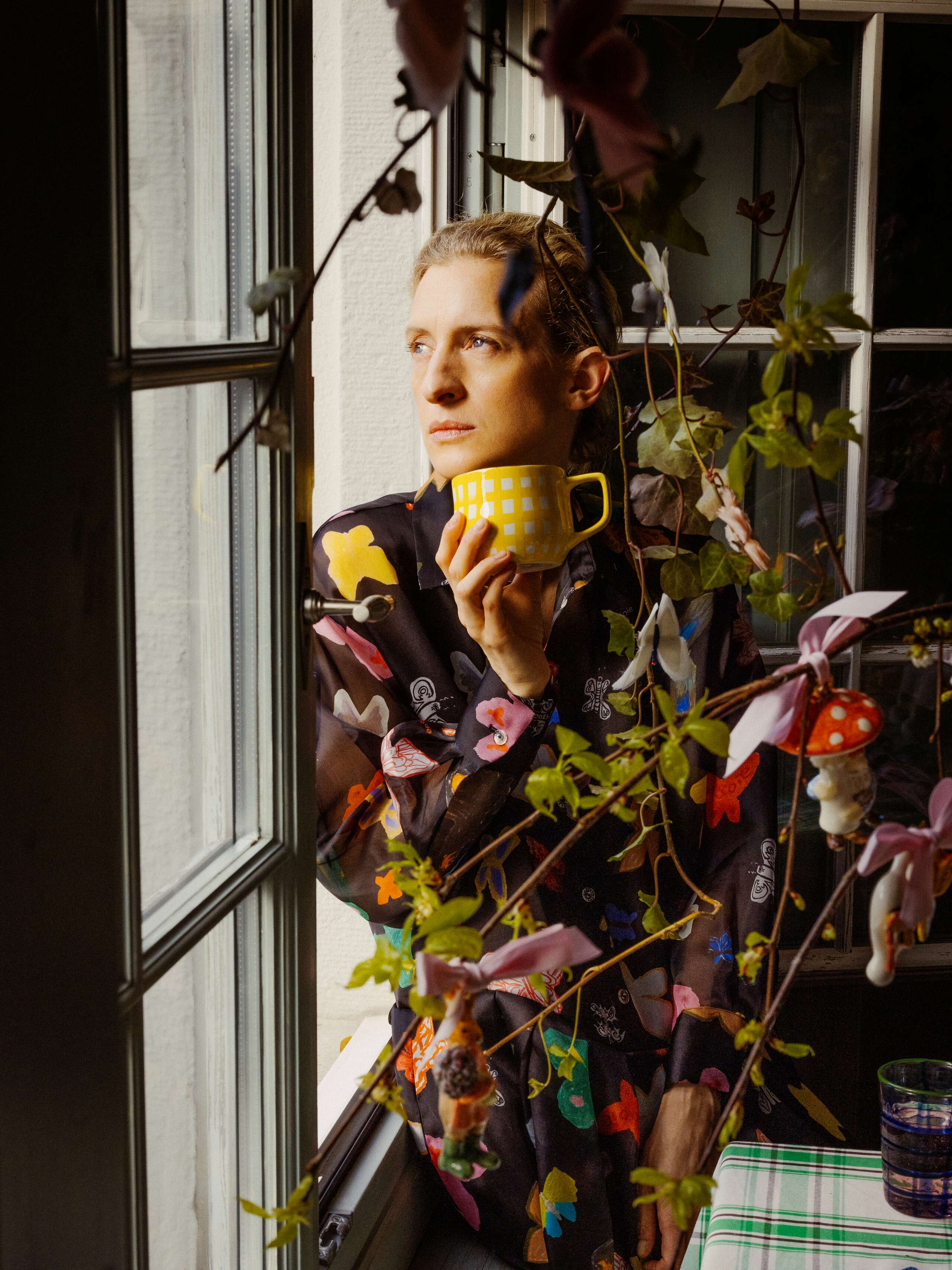 Picture of a women sitting on a window sill drinking a cup of coffee 