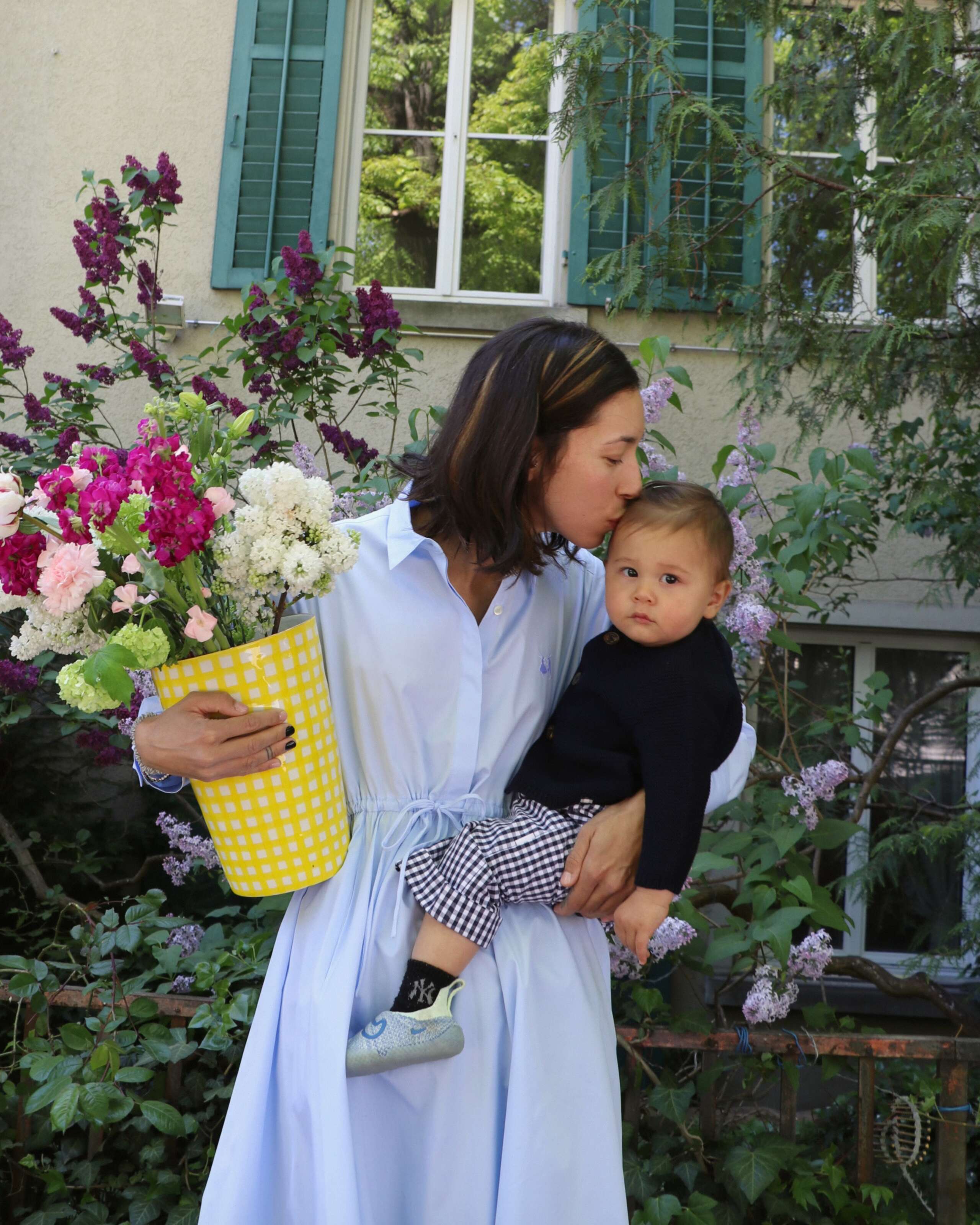 A mother with her small son on her arm, holding a vase filled with flowers