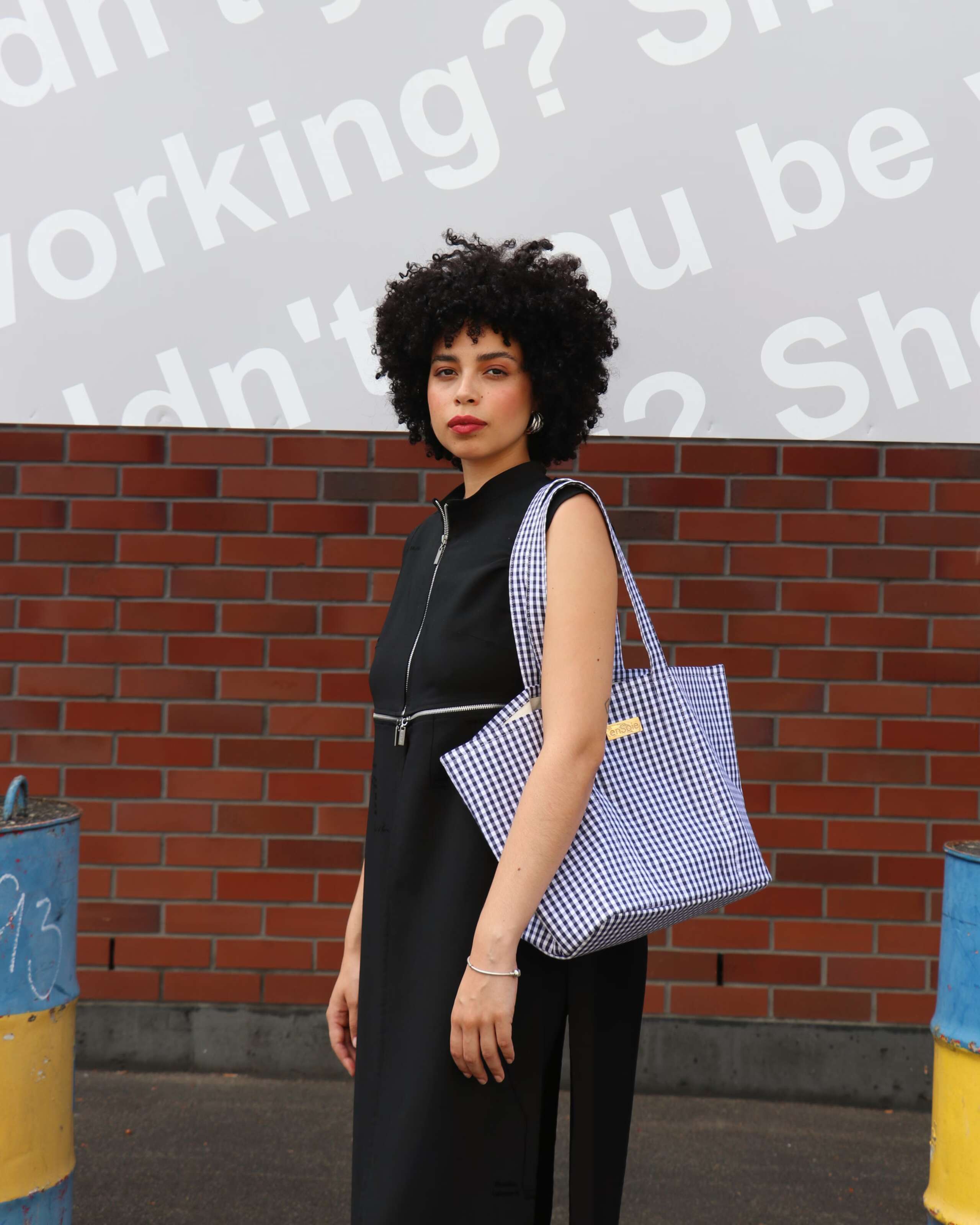 Picture of a women standing in front of a brick wall carrying the new Academia bag by enSoie