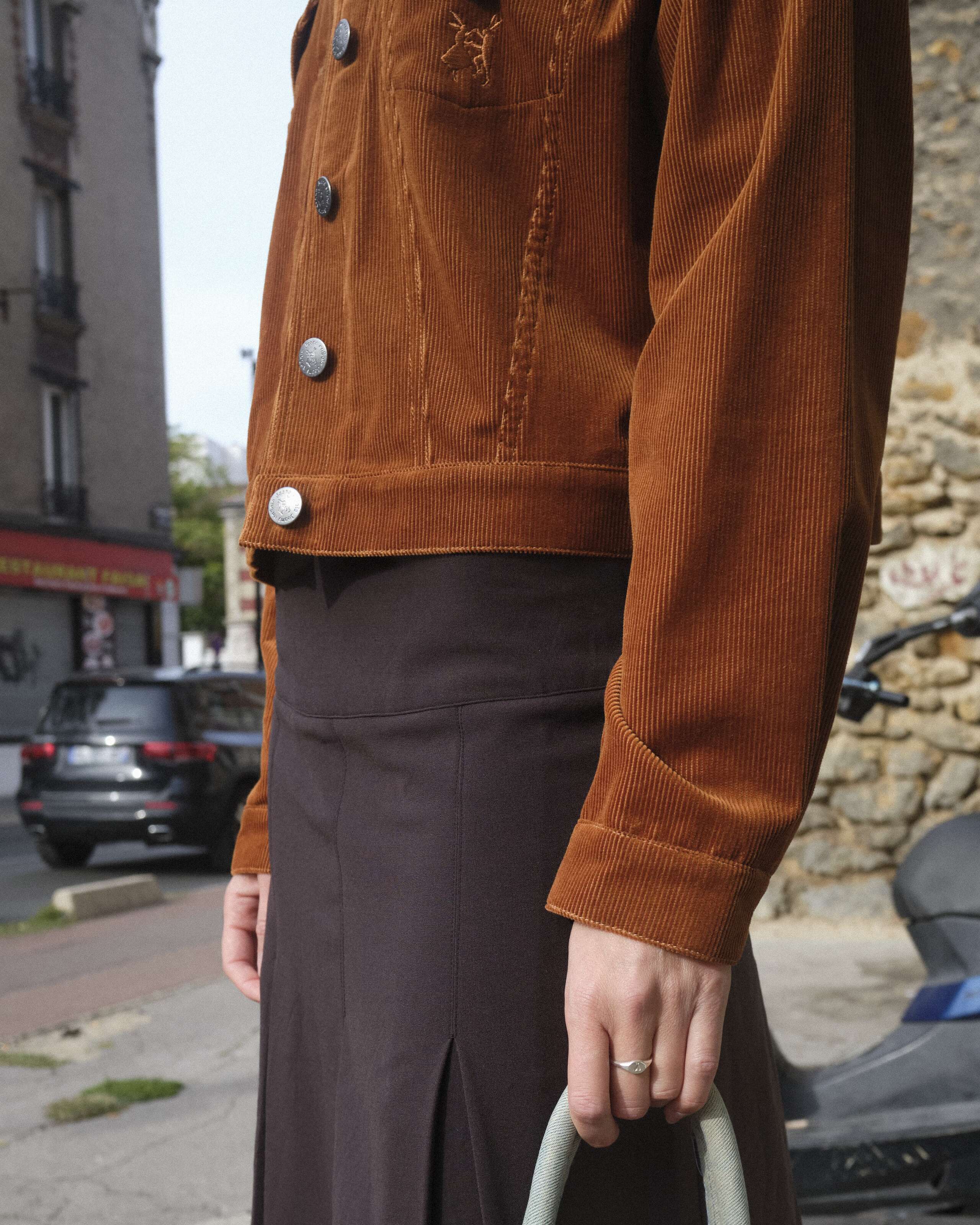 A young women is standing in front of a wall wearing the enSoie Jill jacket