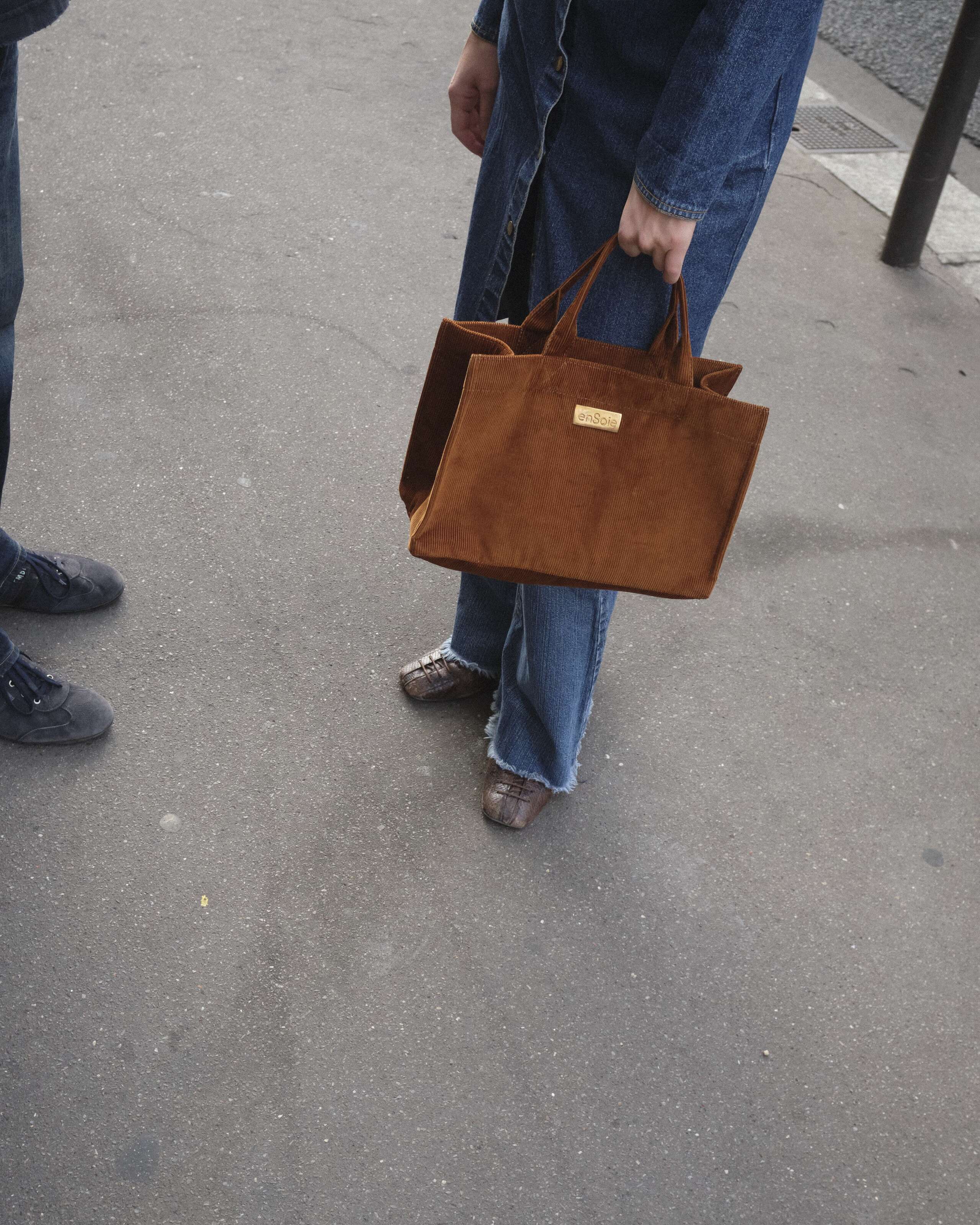 Picture of a women carrying a brown boxy velvet bag by enSoie.
